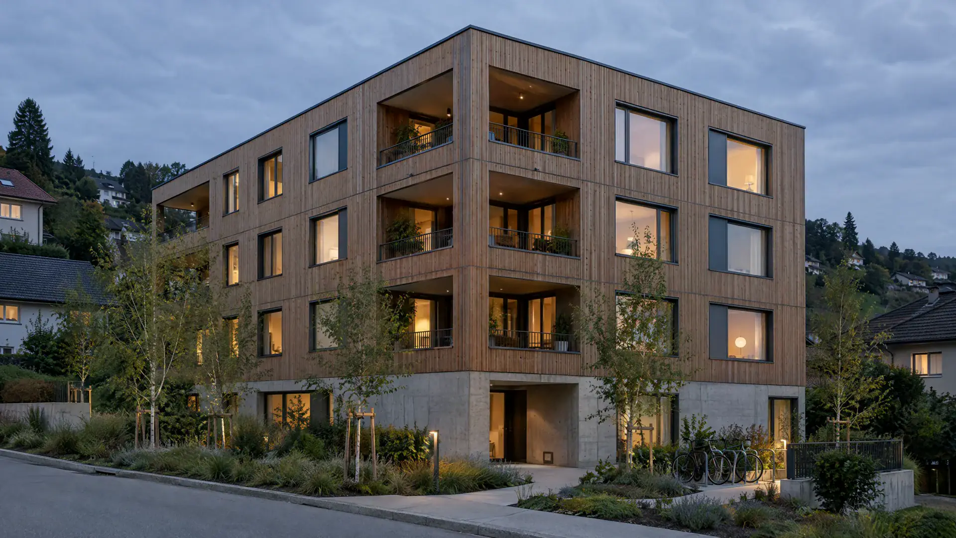 Viergeschossiges Wohnhaus mit Holzfassade am Abend, fertig gebaut, die Fenster beleuchtet.